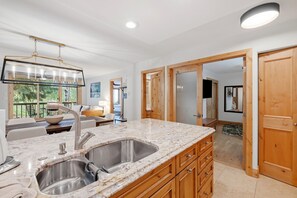 A modern kitchen with a marble countertop, stainless steel sink, and wooden cabinets. - Luxury Amenities, Beaver Creek Ski-In/Ski-Out | LB201 (Beaver Creek)
