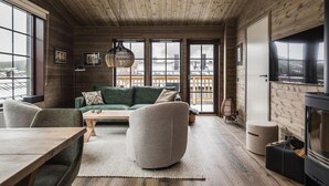 L’intérieur d’un chalet accueillant, avec un plafond en bois, un canapé vert, une table en bois et une cheminée.