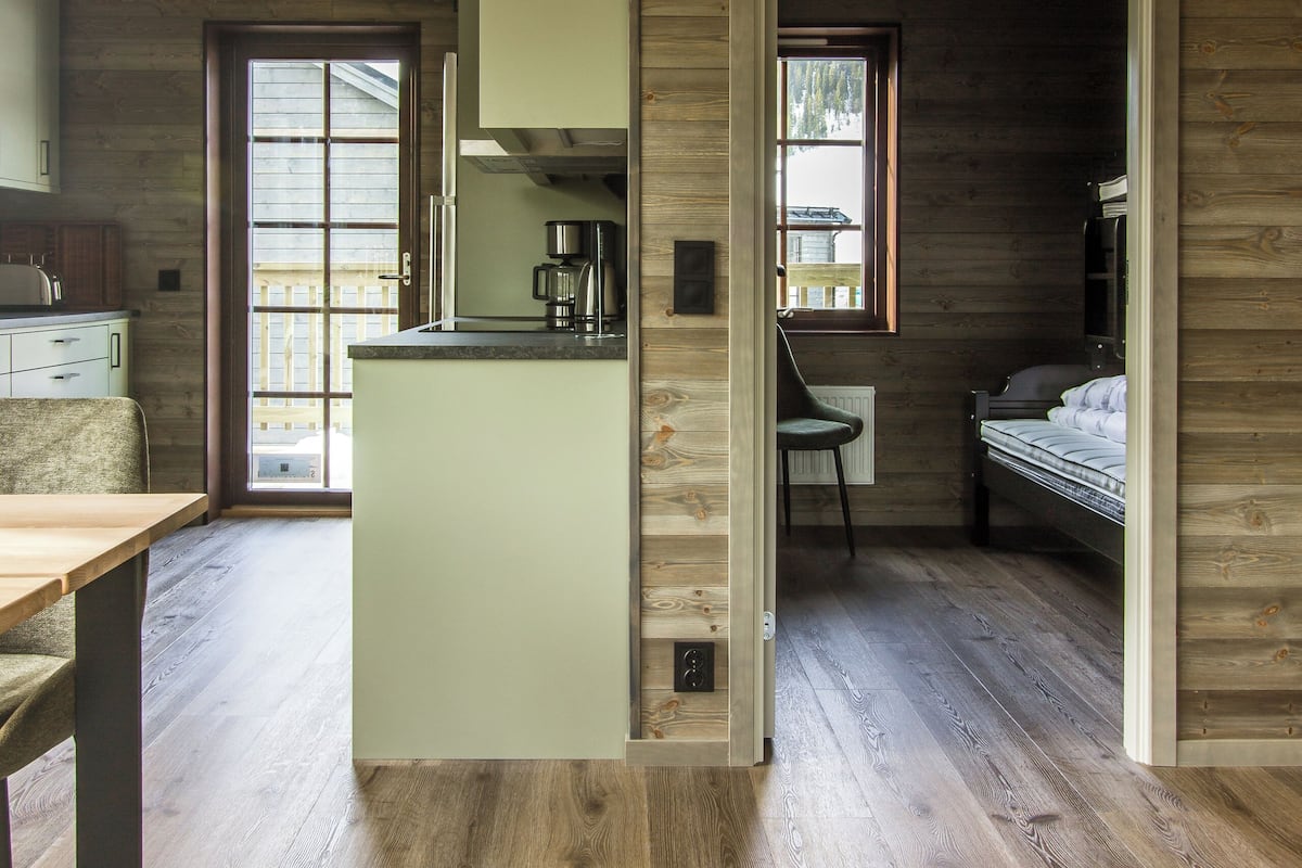 Un interior de madera con una cocina, una mesa de comedor y una cama.