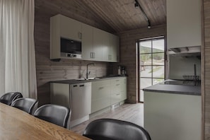 A modern kitchen with white cabinets, a dishwasher, and a large window.
