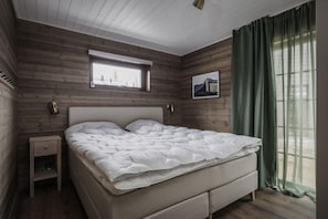 Um quarto com uma cama, uma mesa de cabeceira, uma janela e um quadro na parede.