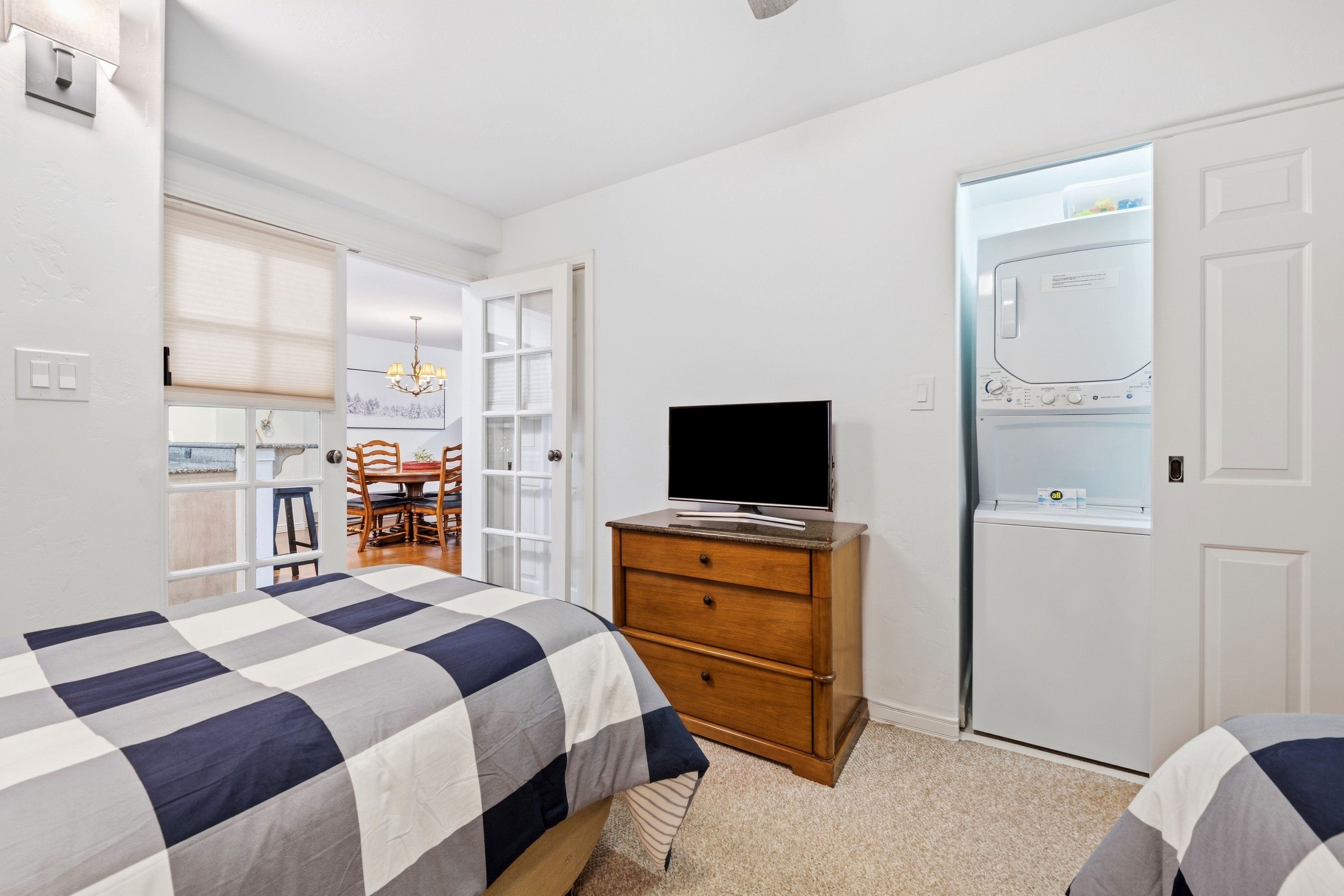 Une chambre à coucher avec un lit, une commode, un téléviseur et un placard.