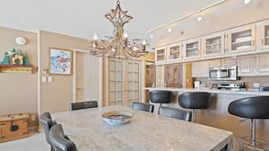 A dining area with a marble table, chairs, a chandelier, and a kitchen in the background. - Beaver Creek Ski-In/Ski-Out w/Amenities | LB205 (Beaver Creek)