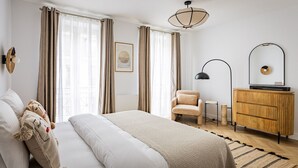 Un dormitorio con cama, una silla, un tocador y una lámpara en el techo.
