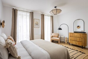 Ein Schlafzimmer mit Bett, Stuhl, Kommode und Deckenleuchte.