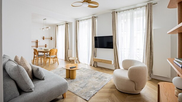 Una sala de estar moderna con un sofá, un sillón, una mesa de comedor y un televisor.