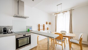 Una cocina moderna con horno empotrado, un comedor con mesa y sillas de madera, y un amplio ventanal con cortinas.