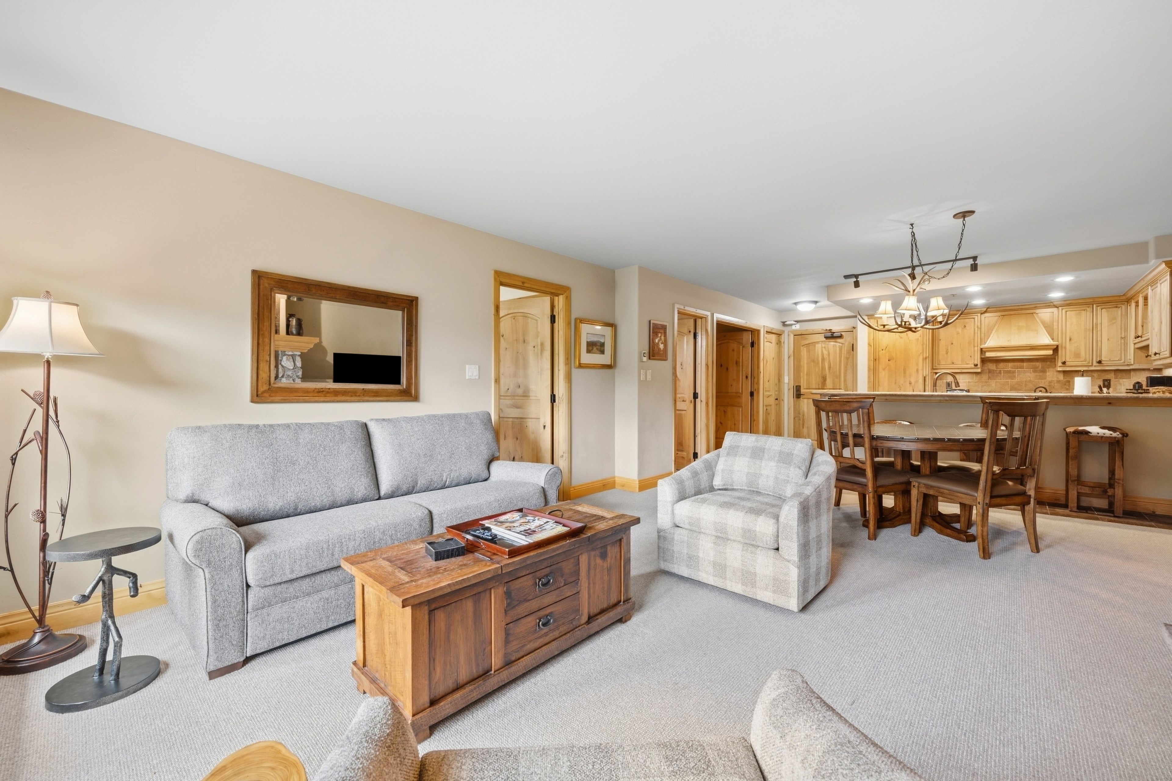A living room with a sofa, armchair, coffee table, and a dining area with a table and chairs.