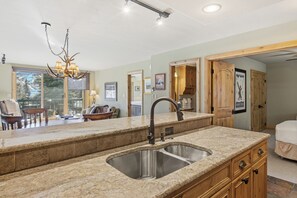 A kitchen with granite countertops, a double sink, and a chandelier. - Ski-In/Ski-Out, Pool, Hot Tubs, Fitness Room | LB208 (Beaver Creek)