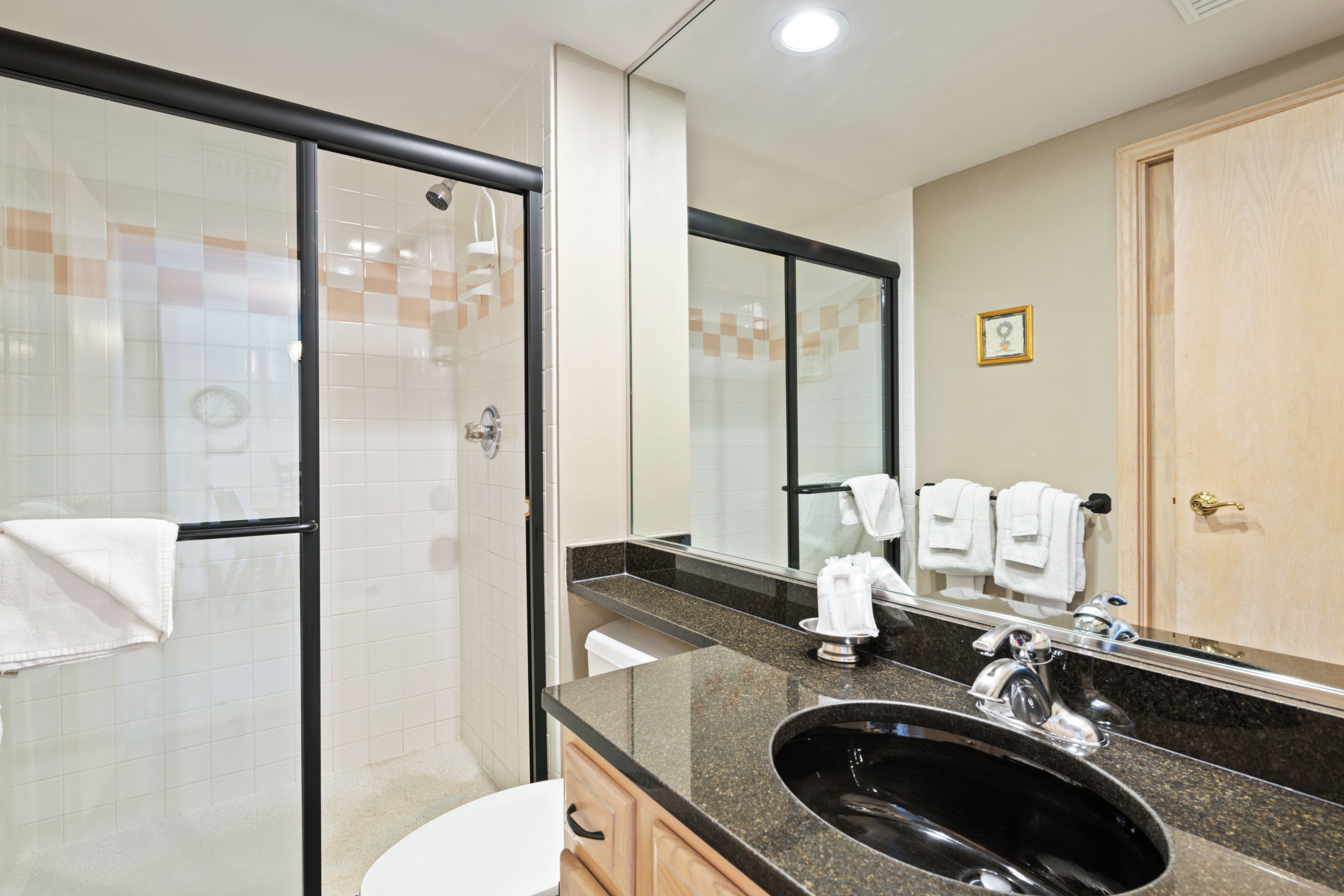 Une salle de bain moderne avec une douche à parois de verre, un lavabo avec un miroir au-dessus et une porte en bois.