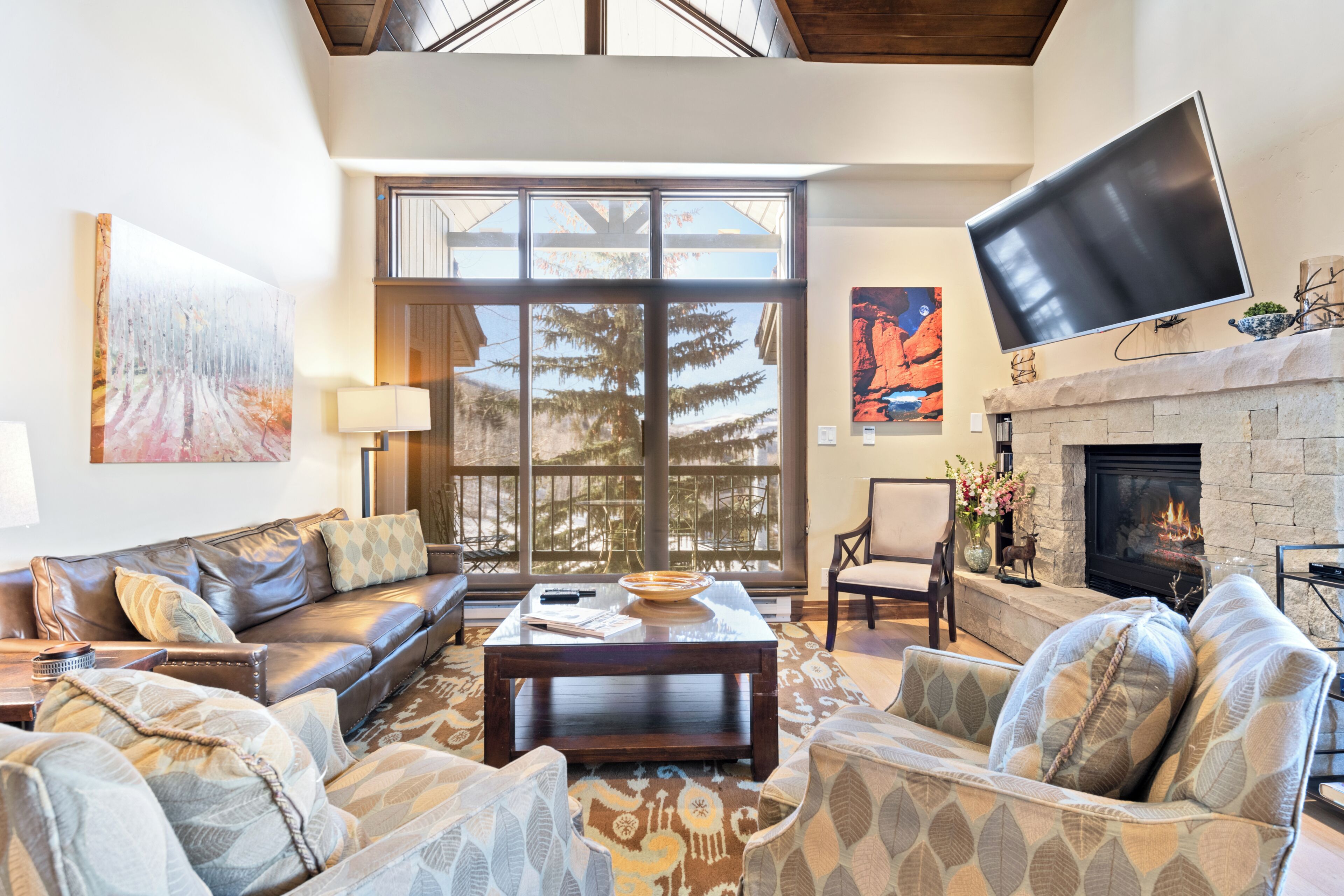 A spacious living room with a fireplace, large windows, and a flat-screen TV.