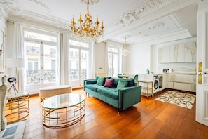 Ein geräumiges Wohnzimmer mit einem grünen Sofa, einem Glastisch und einer Chandelier.