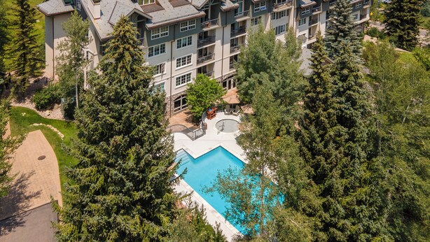 Ein mehrstöckiges Hotel mit Schwimmbad, umgeben von Bäumen.