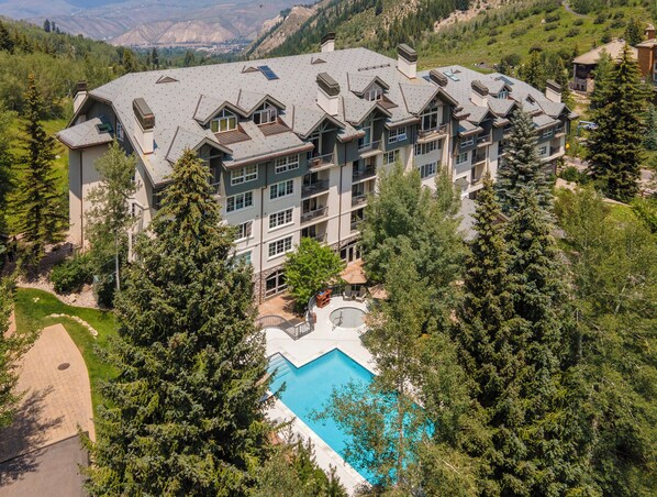 Ein mehrstöckiges Hotel mit Schwimmbad, umgeben von Bäumen.