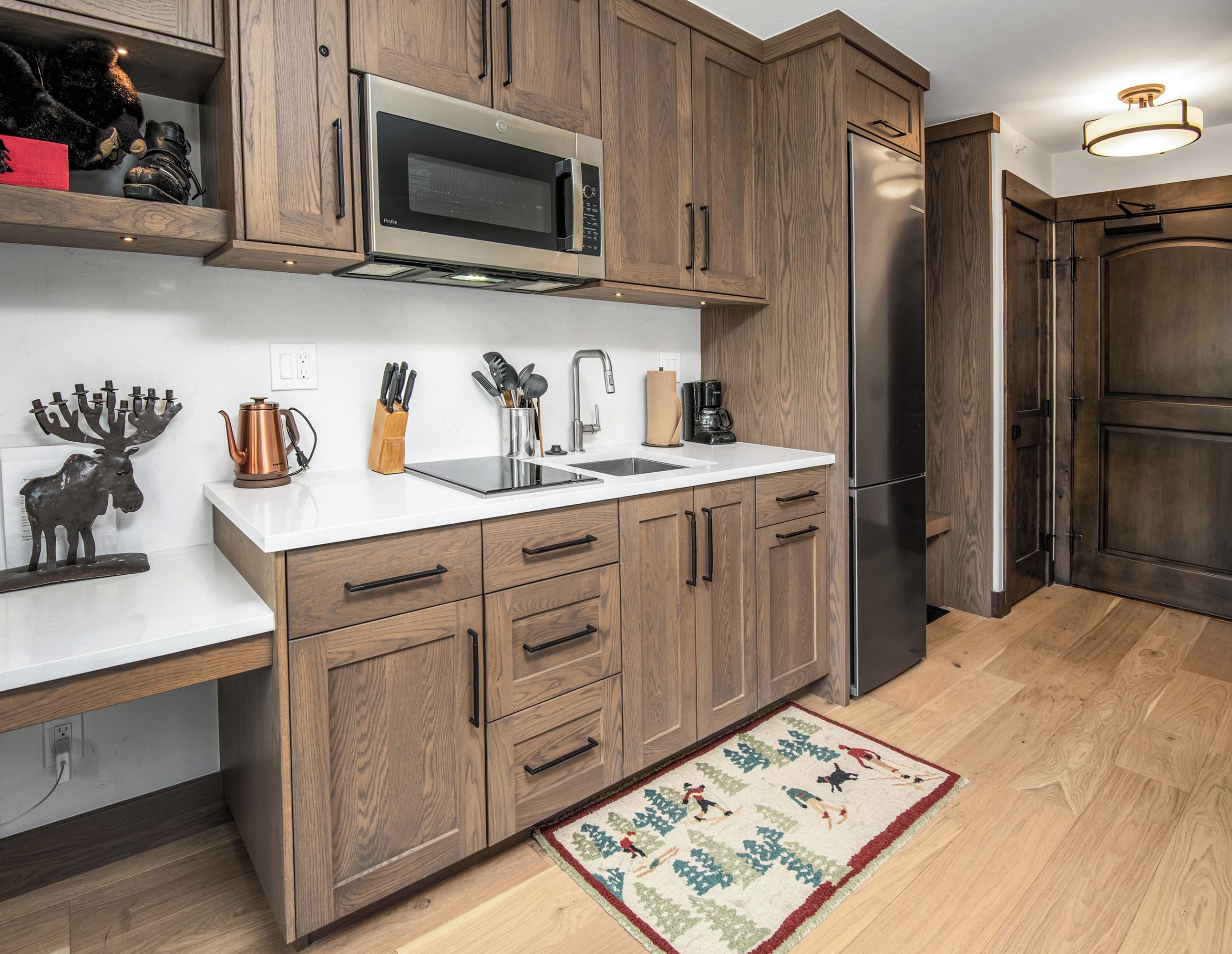 A kitchen with wooden cabinets, a stainless steel refrigerator, a microwave, a sink, and a coffee maker.