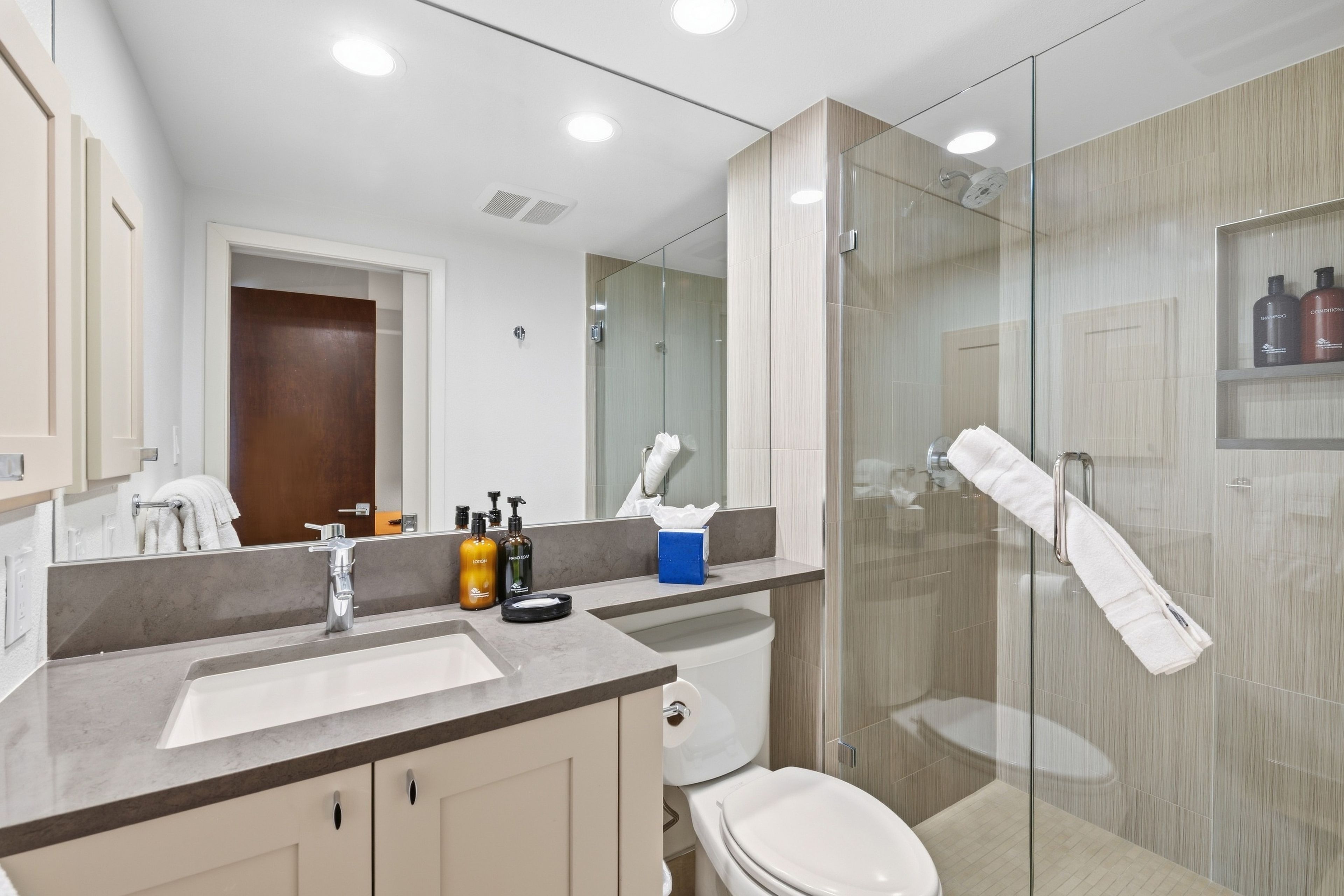 Een moderne badkamer met een glazen douchecabine, een wastafelmeubel met een wastafel en een toilet.