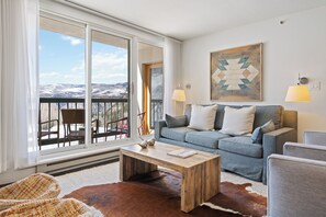 A living room with a sofa, a coffee table, and a view through large windows. - Beaver Creek Ski-In/Ski-Out w/Amenities | LB305   2 Bedroom (Beaver Creek)