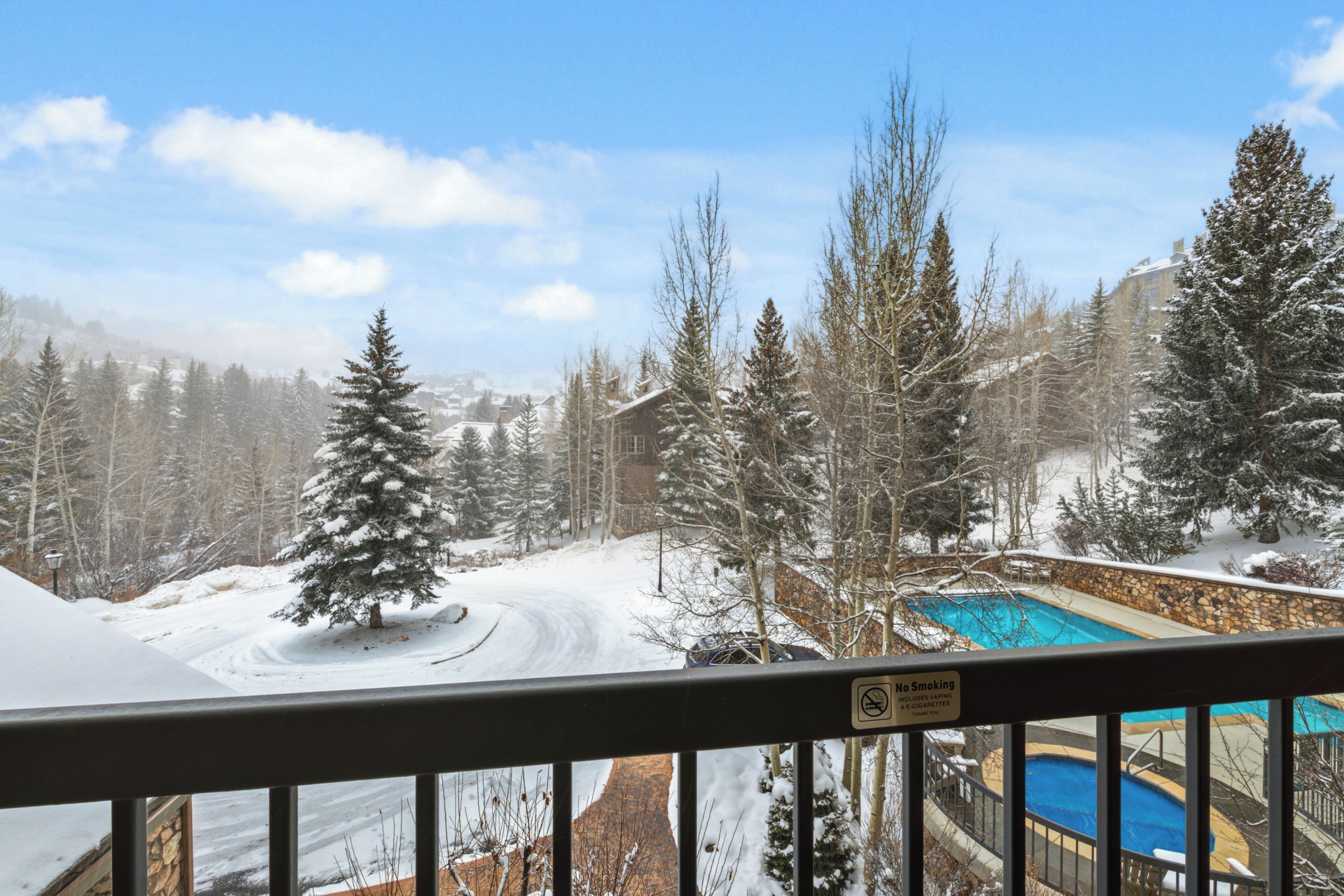 A snowy landscape with a pool area, a no smoking sign, and a view of a mountain.