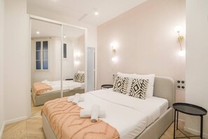 A bedroom with a bed, a mirror, a bedside table, and a wall-mounted light fixture. - Champs Elysées!Montaigne, New&Luxurious 6pers flat (Paris)