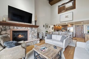 A living room with a stone fireplace, a flat-screen TV, a sofa, and a coffee table. - Ski-In/Ski-Out, Resort Amenities, Shuttle | LB309  3 Bedroom (Beaver Creek)