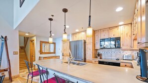 Una cocina con armarios de madera, un refrigerador de acero inoxidable, un microondas y una isla grande con taburetes de bar.