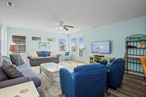 Ein Wohnzimmer mit Deckenventilator, Fernseher und Bücherregal.