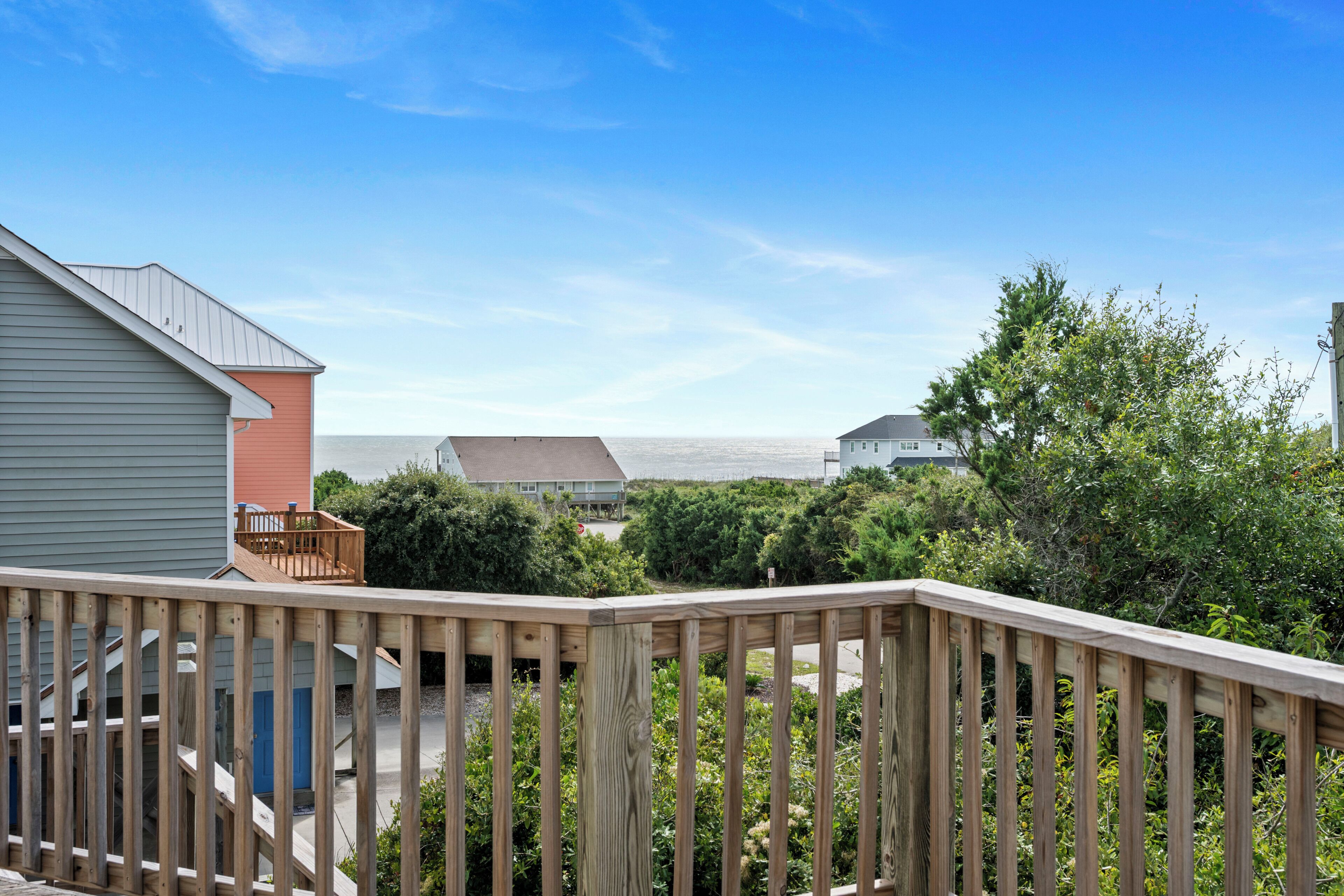 A residential area with a wooden deck, a staircase leading to a porch, and houses in the background.