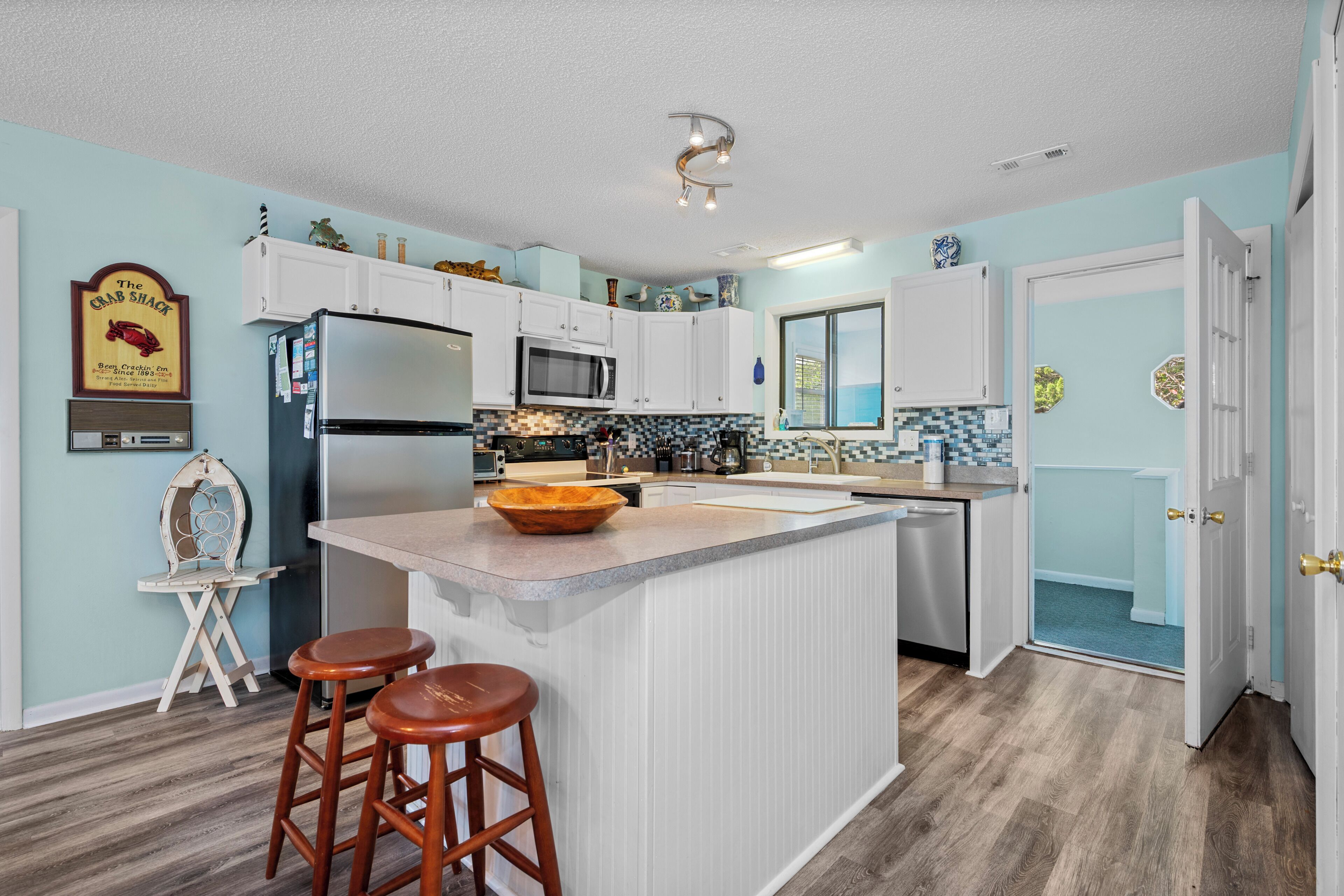 A kitchen with a central island, white cabinets, a refrigerator, and a microwave.