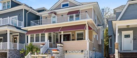 A two-story residential building with a balcony, a garage, and a stone facade.