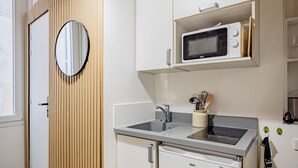 Une cuisine compacte équipée d’un four à micro-ondes, d’un petit réfrigérateur et d’un évier.