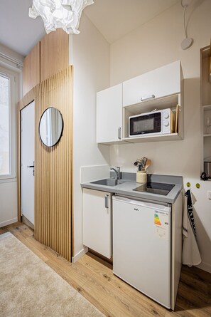 A compact kitchen with a microwave, a small refrigerator, and a sink. - Batignolles - Cosy renovated studio apartment (Paris)