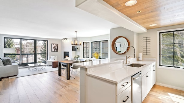 Amplia sala de estar con isla de cocina, ventanas grandes y techo de madera.