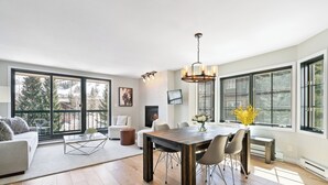 Un salón espacioso con comedor, ventanas amplias y chimenea.