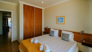 A hotel room with a large bed, wooden wardrobe, and a painting on the wall. - FLH Monte Gordo Balcony Flat (Monte Gordo)