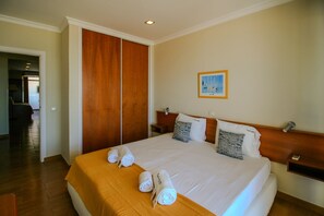 A hotel room with a large bed, wooden wardrobe, and a painting on the wall. - FLH Monte Gordo Balcony Flat (Monte Gordo)