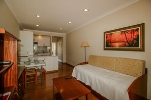 A hotel room with a kitchenette, a dining area, a sofa, and a painting on the wall. - FLH Monte Gordo Balcony Flat (Monte Gordo)
