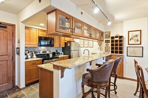 A kitchen with wooden cabinets, granite countertops, a refrigerator, a microwave, and a coffee maker. - Luxury Amenities, Beaver Creek Ski-In/Ski-Out| LB405 (Beaver Creek)