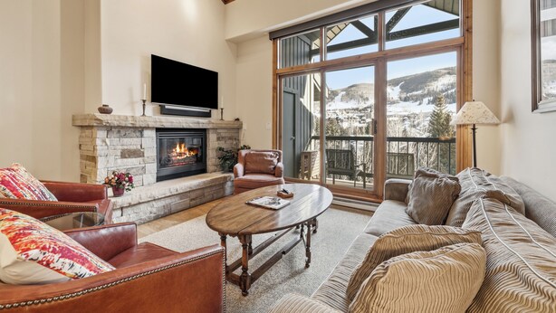 A living room with a fireplace, leather furniture, and a large window with a view. - Beaver Creek Slope-Side Luxury | LB504 (Beaver Creek)
