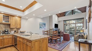 A spacious kitchen with wooden cabinets, a large island, and a dining area with chairs and a table. - Beaver Creek Slope-Side Luxury | LB504 (Beaver Creek)