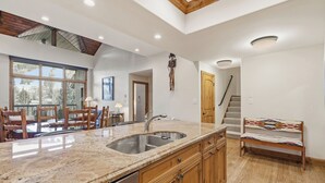 A kitchen with a granite countertop, stainless steel sink, wooden cabinets, and a bench. - Beaver Creek Slope-Side Luxury | LB504 (Beaver Creek)