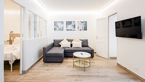 A modern living room with a grey sofa, a round coffee table, and artwork on the wall. - Cœur Batignolles-Europe-2 rooms-charm-Paris 8 (Paris)