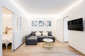 Ein modernes Wohnzimmer mit einem grauen Sofa, einem runden Couchtisch und Kunstwerken an der Wand.