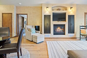 Ein Wohnzimmer mit Kamin, Glastisch, Sofa und Sessel.