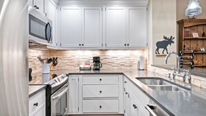 A modern kitchen with white cabinets, a microwave, a coffee maker, and a sink. - Beaver Creek Slope-Side Luxury | UB108 (Beaver Creek)
