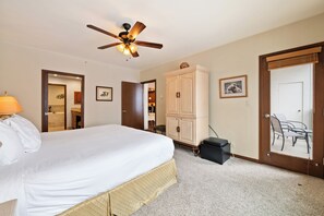 A hotel room with a bed, a ceiling fan, a cabinet, a door, and a chair. - Beaver Creek Slope-Side Luxury | UB203 (Beaver Creek)