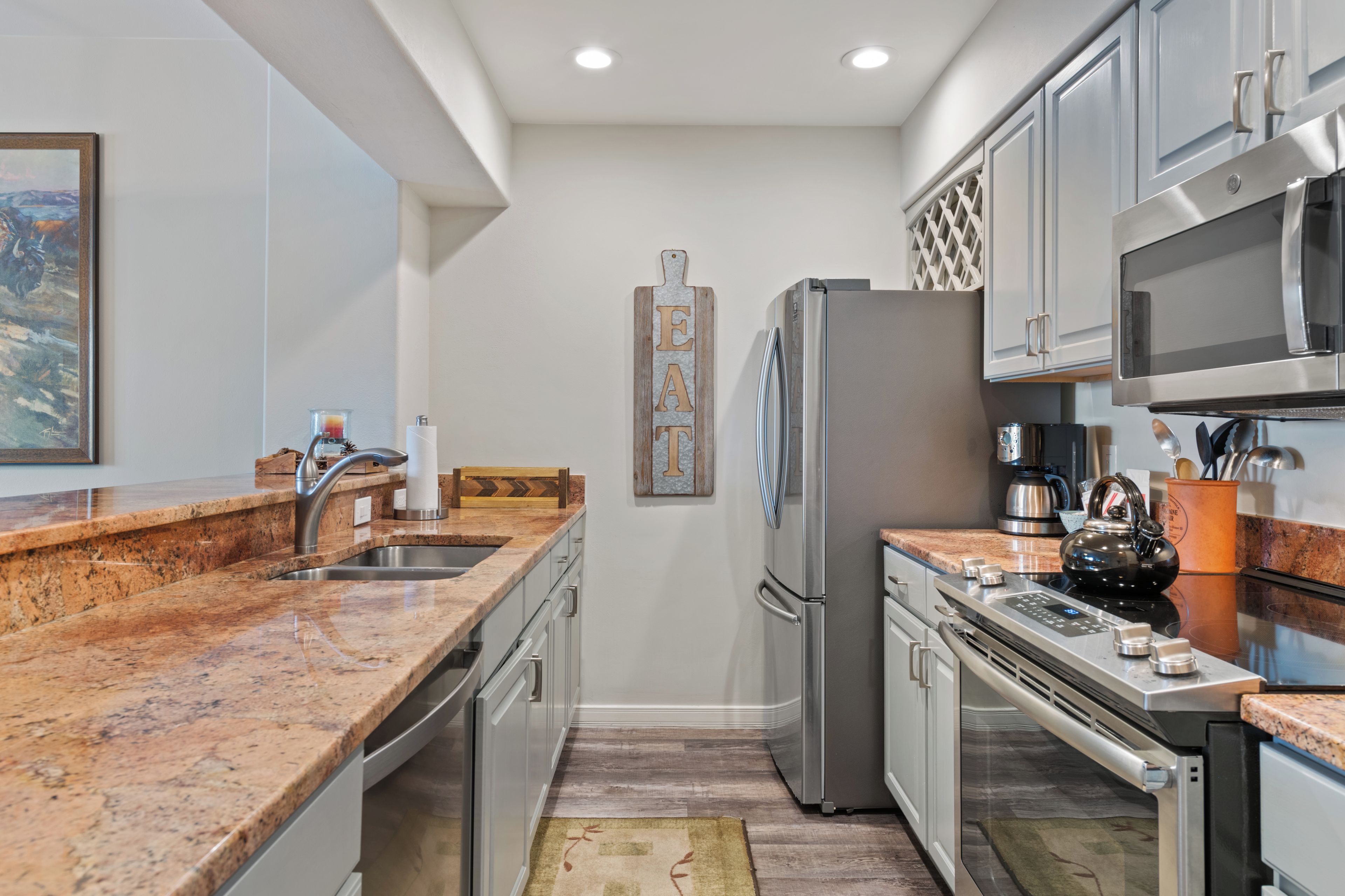A modern kitchen with granite countertops, stainless steel appliances, and a wooden backsplash.