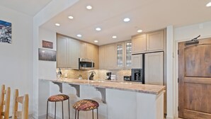 Una cocina moderna con una isla central, electrodomésticos de acero inoxidable y una puerta de madera.