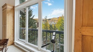 Ein Zimmer mit großem Fenster, einem Teleskop und einem Holzkabinett.