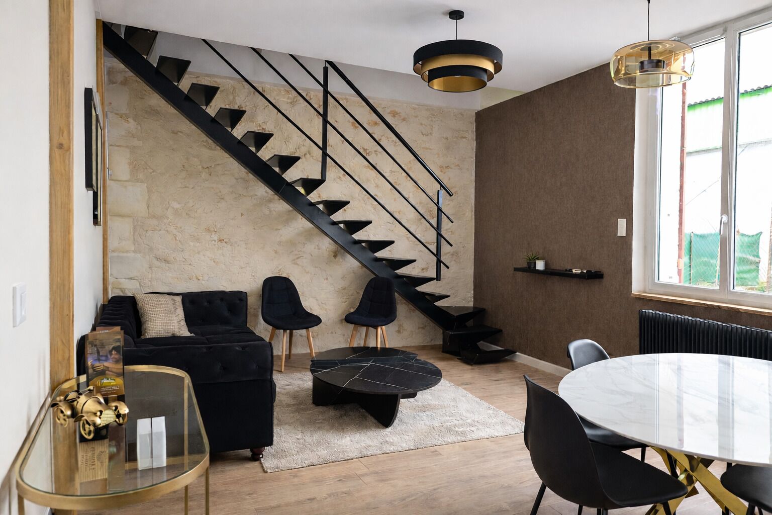 Ein modernes Wohnzimmer mit Treppe, einem runden Esstisch und einer Couch.