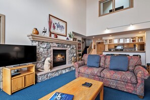 Ein Wohnzimmer mit Kamin aus Stein, einem Flachbildfernseher, einer Couch und einem Couchtisch.